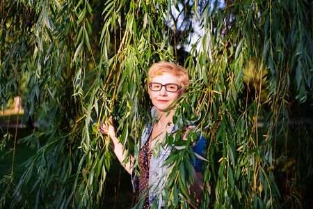 Portrait of  stylish   middle aged woman smiling on the nature tree backgroundの写真素材