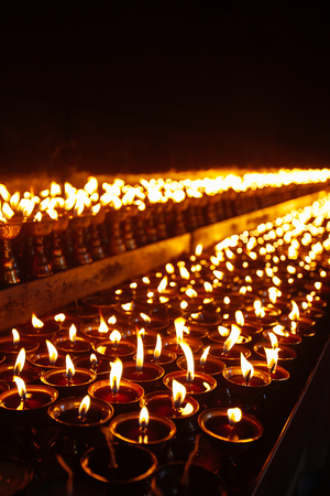 Many candle flames glowing in the dark with shallow depth of fieldの写真素材