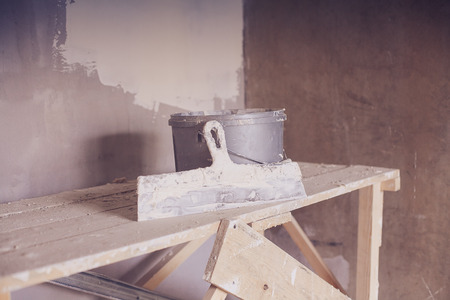 Set of plaster trowel tool, spatula and bucket. Construction tools in empty roomの写真素材