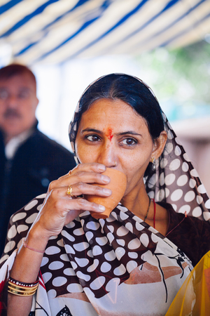 PUSHKAR, INDIA - JAN 16, 2017 Woman drinking masala tea on the street in india in Pushkar, Rajasthan.のeditorial素材