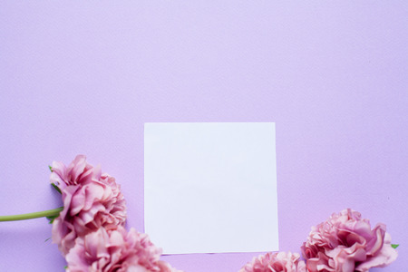 Mockup on violet background with white paper sheet and peony flowers, top view. Flat lay styleの写真素材