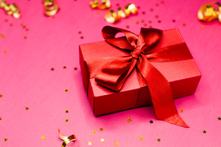 Red gift box and Golden decorations and sparkles on bright  pink background