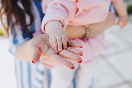 Mother tenderly holding fingers of the baby.  Baby care conceptの写真素材