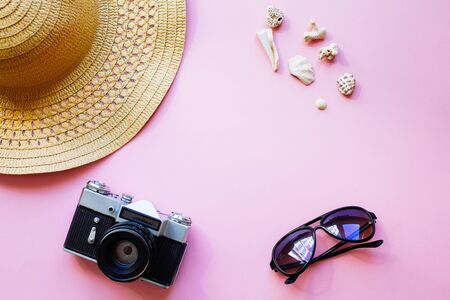 Flat lay design of travel concept with camera, hat, shells on pink backgroundの写真素材