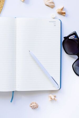 Flat lay design of travel concept with camera, notebook, hat, shells on white backgroundの写真素材