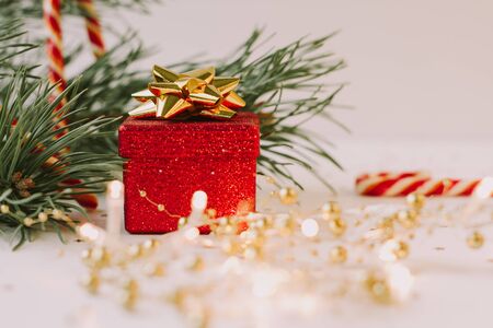 Christmas composition. Fir tree branch, red gift box, candy canes with gold confetti on white  background. Christmas, winter, new year conceptの写真素材