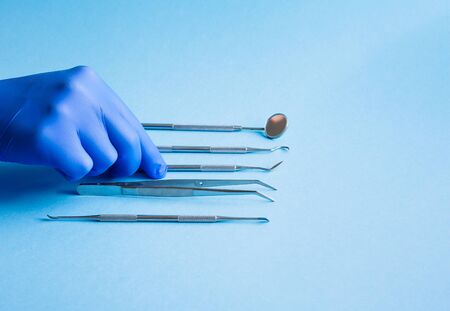 Dentist choose or rearrange set of dentist tools on blue background: Dental Hygiene and Health conceptual imageの写真素材