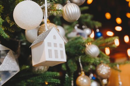 Decorated Christmas tree with house toy on blurred, sparkling and fairy backgroundの写真素材