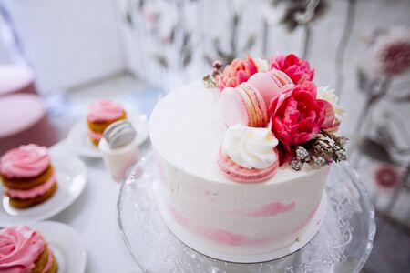 Beautifully decorated catering banquet table with white cake with red flowers on the top. Event or...
