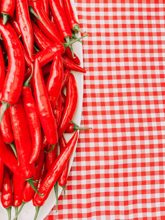 Beautiful red peppers or chilies on red plaid tablecloth background. Fresh Red hot chili pepperの写真素材