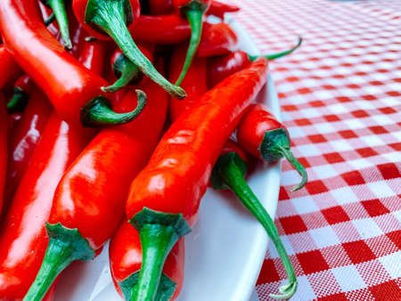 Beautiful red peppers or chilies on red plaid tablecloth background. Fresh Red hot chili pepperの写真素材