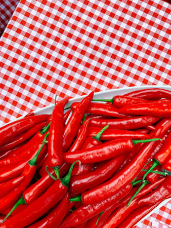 Beautiful red peppers or chilies on red plaid tablecloth background. Fresh Red hot chili pepperの写真素材