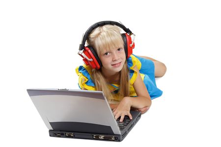 The girl with headphones lays before a portable computer on a white backgroundの写真素材