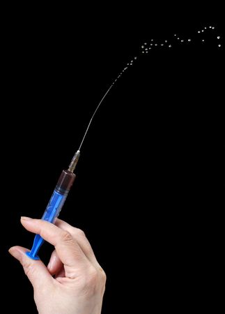 Syringe in a hand on a black backgroundの写真素材