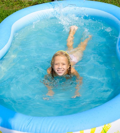 A smiling girl bathes in pool and sprays waterの写真素材