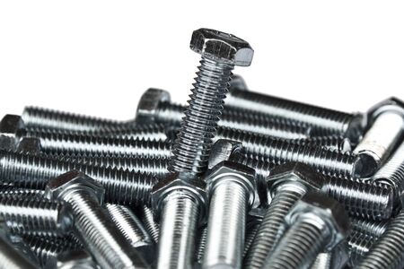 Macro of one outstanding bolt amoung a pile of bolt isolated on white, shallow DOF