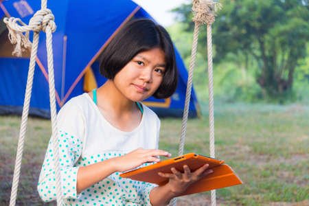 Asian casual girl using tablet on outdoors campingの写真素材