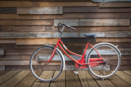 Old bicycle on old plank of wood floor and old wooden wall, with lightingの写真素材