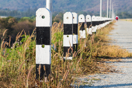 Receding black and white concrete posts as fence or barrier for roadの写真素材