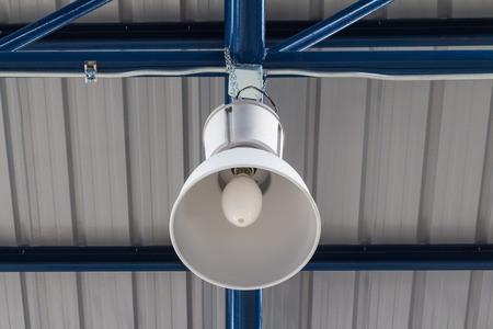 Close up of overhead lighting fixture hanging on factory truss