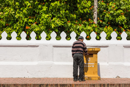 Tourist man sending a mail or postcard by dropping it into the post box on the street, Luang Prabang, Laosのeditorial素材