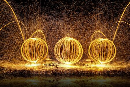 Fire balls of spinning hot steel wool, with water reflection