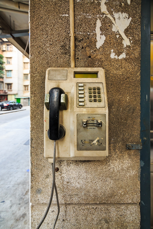 Abandon public card telephone installed on the pole of building for public use in Guangzhou, Chinaの写真素材