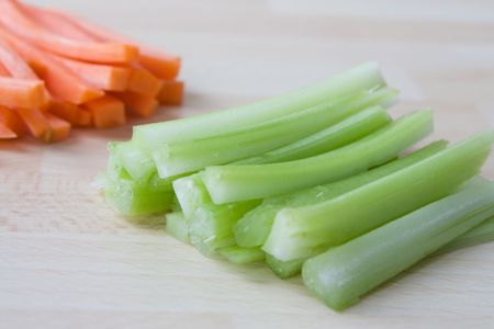 Selective focus image of sliced celery with carrots in the backgroundの写真素材