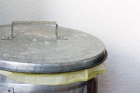 Closeup image of a metal dustbin in front of a white wall.の写真素材