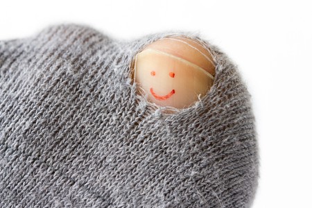 Close-up image of a sock with a hole and a smiley on the toenail.の写真素材