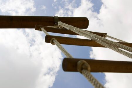 Closeup image of a rope ladder with blue sky as background which can be also used as symbol for...
