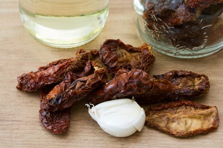 Still life with dried tomatoes, garlic, olive oil and a preserving glass, all things which are needed to preserve tomatoes in oil.の写真素材