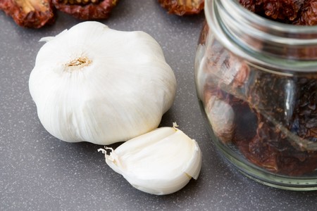 Still life with garlic, dried tomatoes and a preserving glass, all things which are needed to preserve tomatoes in oil.の写真素材