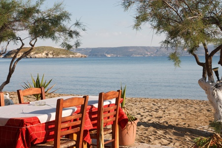 Table and chairs of a Greek taverna at the beach.の写真素材