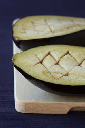 Aubergines which are cut in half on a wooden board.の写真素材