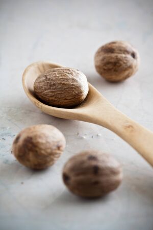Nutmeg and a wooden spoon on stone.の写真素材