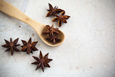 Star Anise and a wooden spoon on stone.