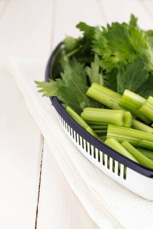 Bowl with sliced celery on a white wooden board.の写真素材