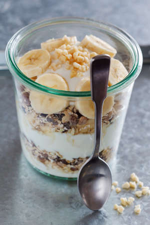 Glass with muesli, banana and spoon.の写真素材