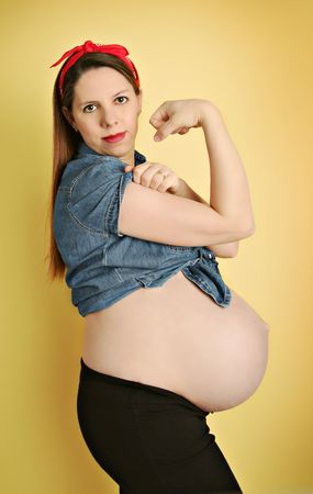 Young pregnant woman showing belly and flexed arm musclesの写真素材