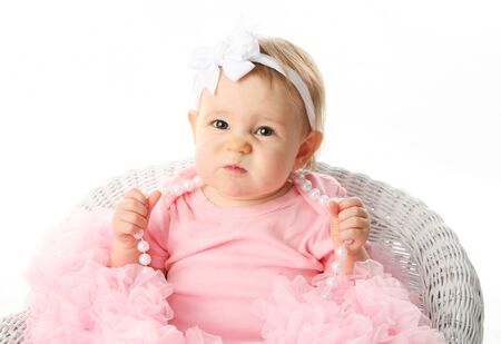 Portrait of a sweet infant wearing a pink tutu, necklace, and headband bow, isolated on white in studio with a funny expression on her face, scrunching up noseの写真素材