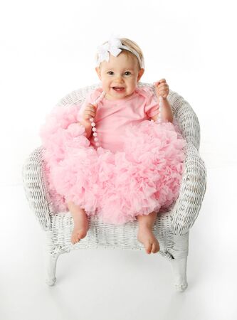 
Portrait of a sweet infant wearing a pink tutu, necklace, and headband bow, isolated on white in studio sitting in a wicker child's chair
の写真素材