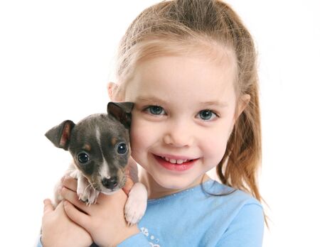 Portrait of an adorable young girl smiling holding a cute tiny rat terrier puppyの写真素材