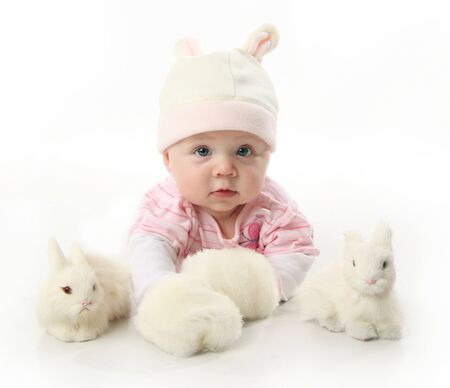 Portrait of an adorable baby girl wearing a bunny rabbit costume and petting two white bunnies
の写真素材