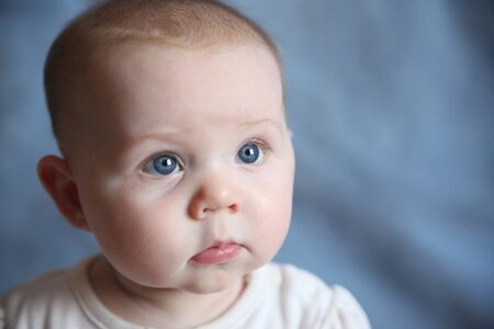 Portrait of adorable baby with big blue eyes on a blue background