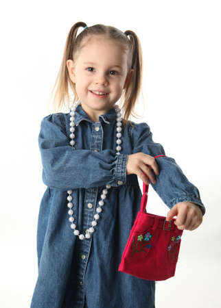 Portrait of an adorable preschool girl playing dress up with a purse and pearl necklace isolated on whiteの写真素材