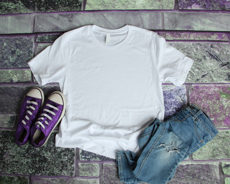 White T Shirt mockup flat lay on purple brick background with purple shoes and ripped jeansの写真素材
