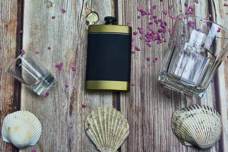 shot glass flask sea shells and a drinking glass on woodの写真素材
