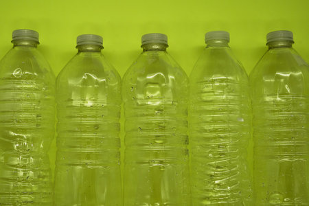 Empty plastic water bottles recycle material reduce waste neon green backgroundの写真素材