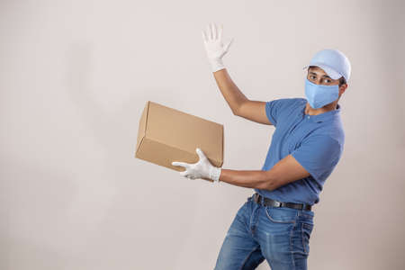 Mexican Latin delivery man carrying a box wearing a face mask due to covid 19 pandemicの写真素材